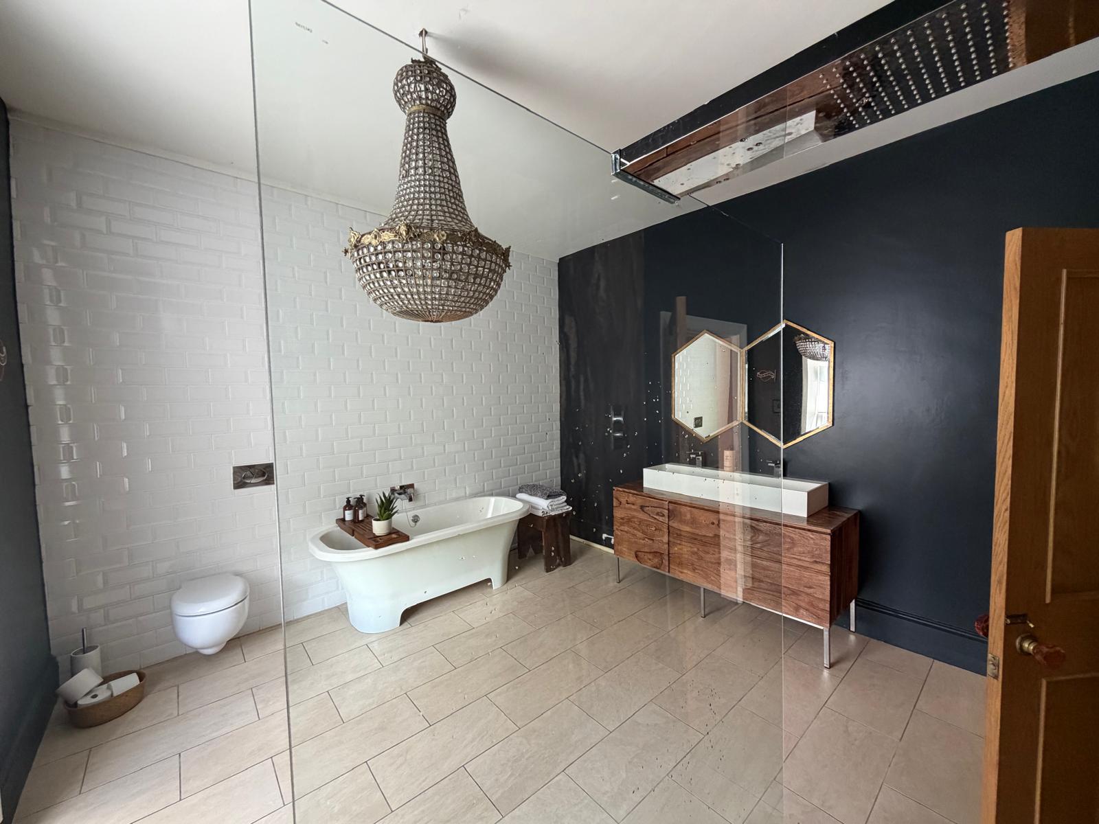 Bathroom with a freestanding tub, glass shower and ornate chandelier