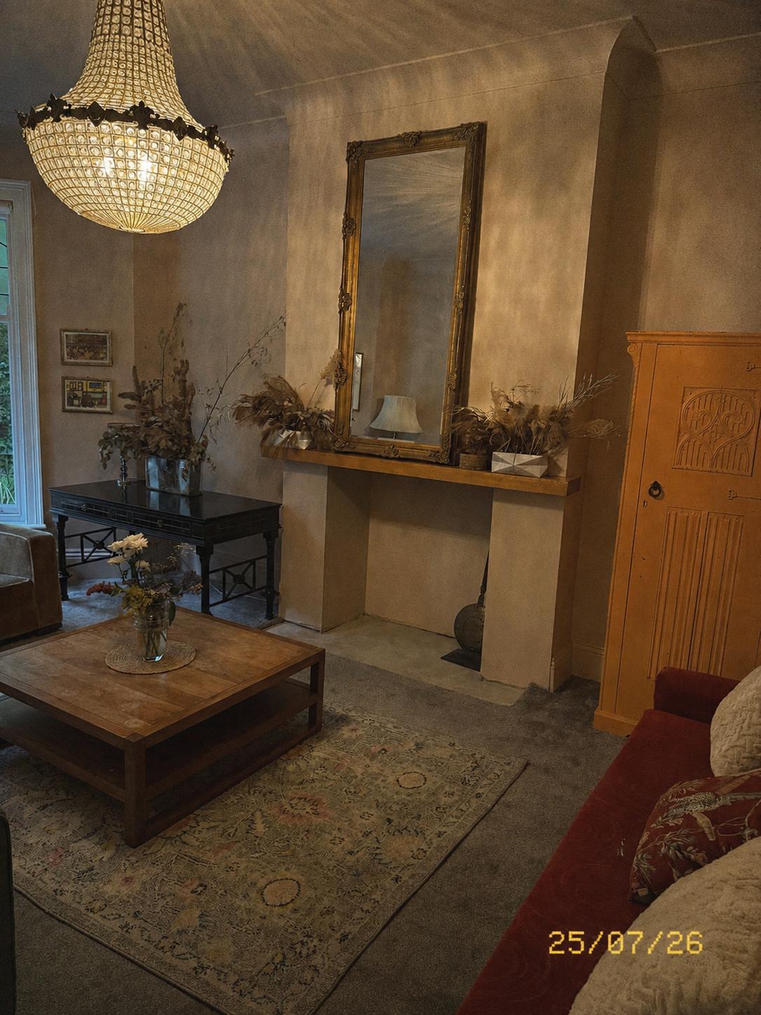Living room with a gilded mirror, dried flowers and a red sofa