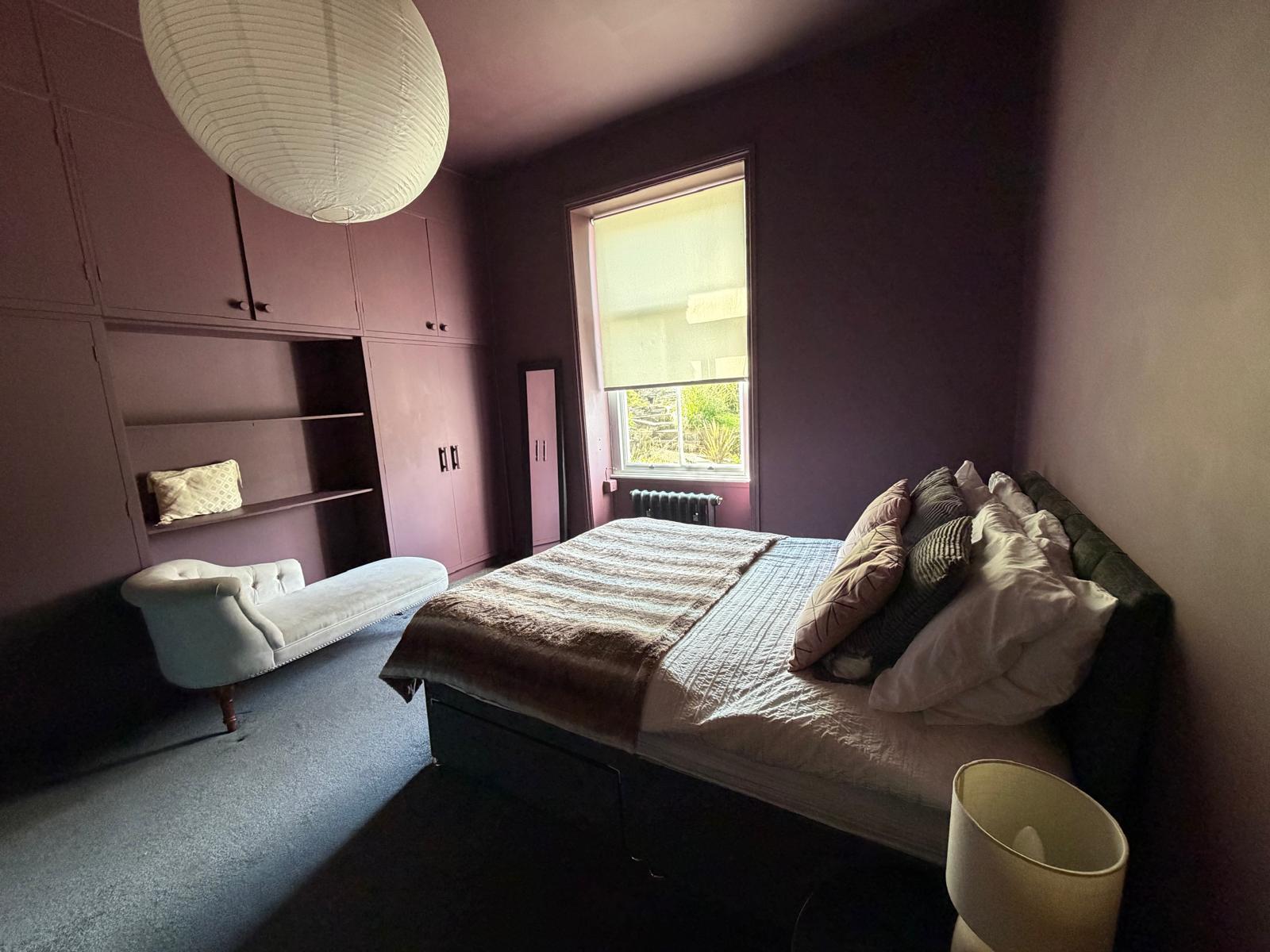 Bedroom with built-in pink wardrobes and a paper lantern shade