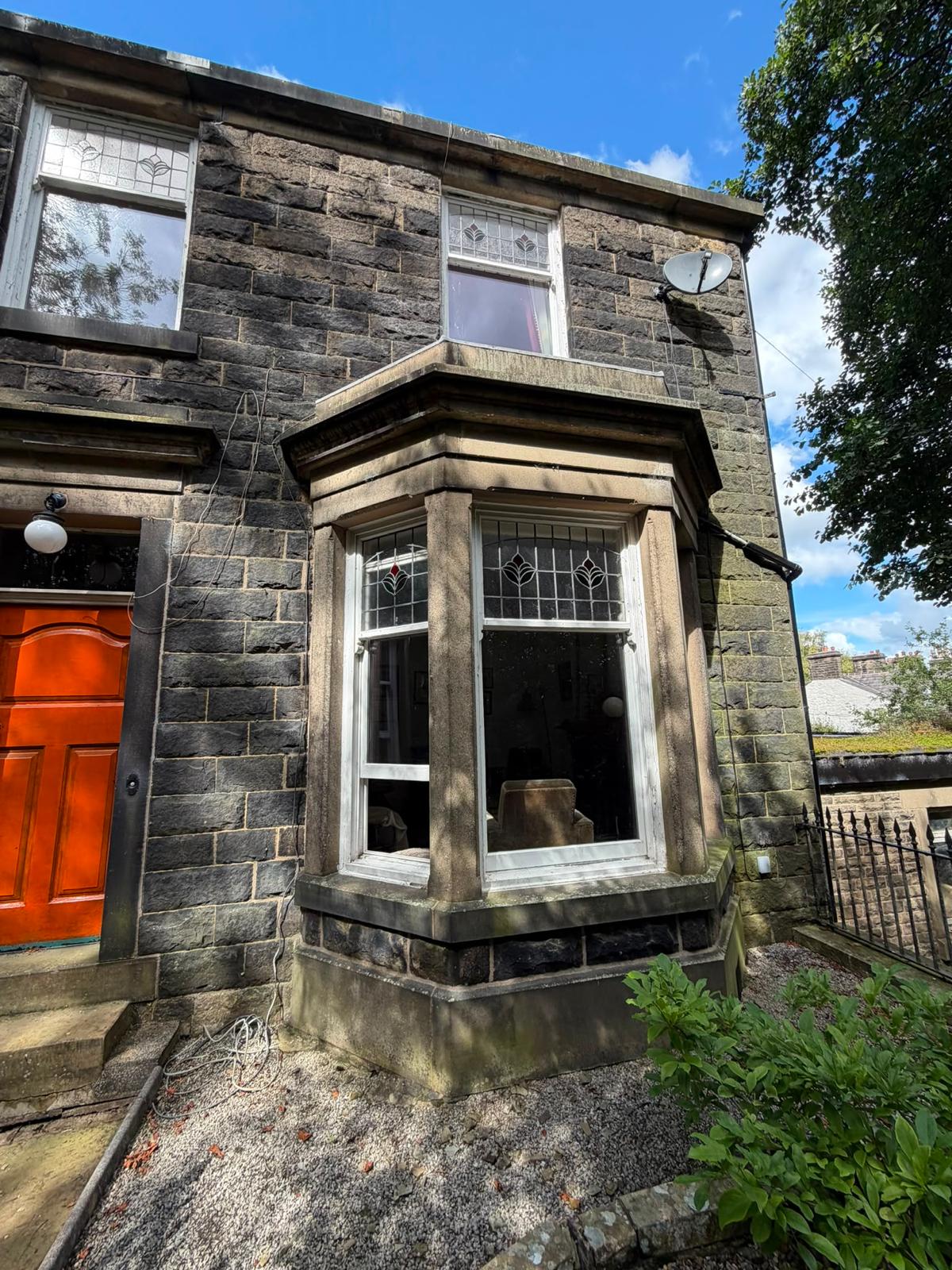 Stone bay window with original leaded glass and orange front door