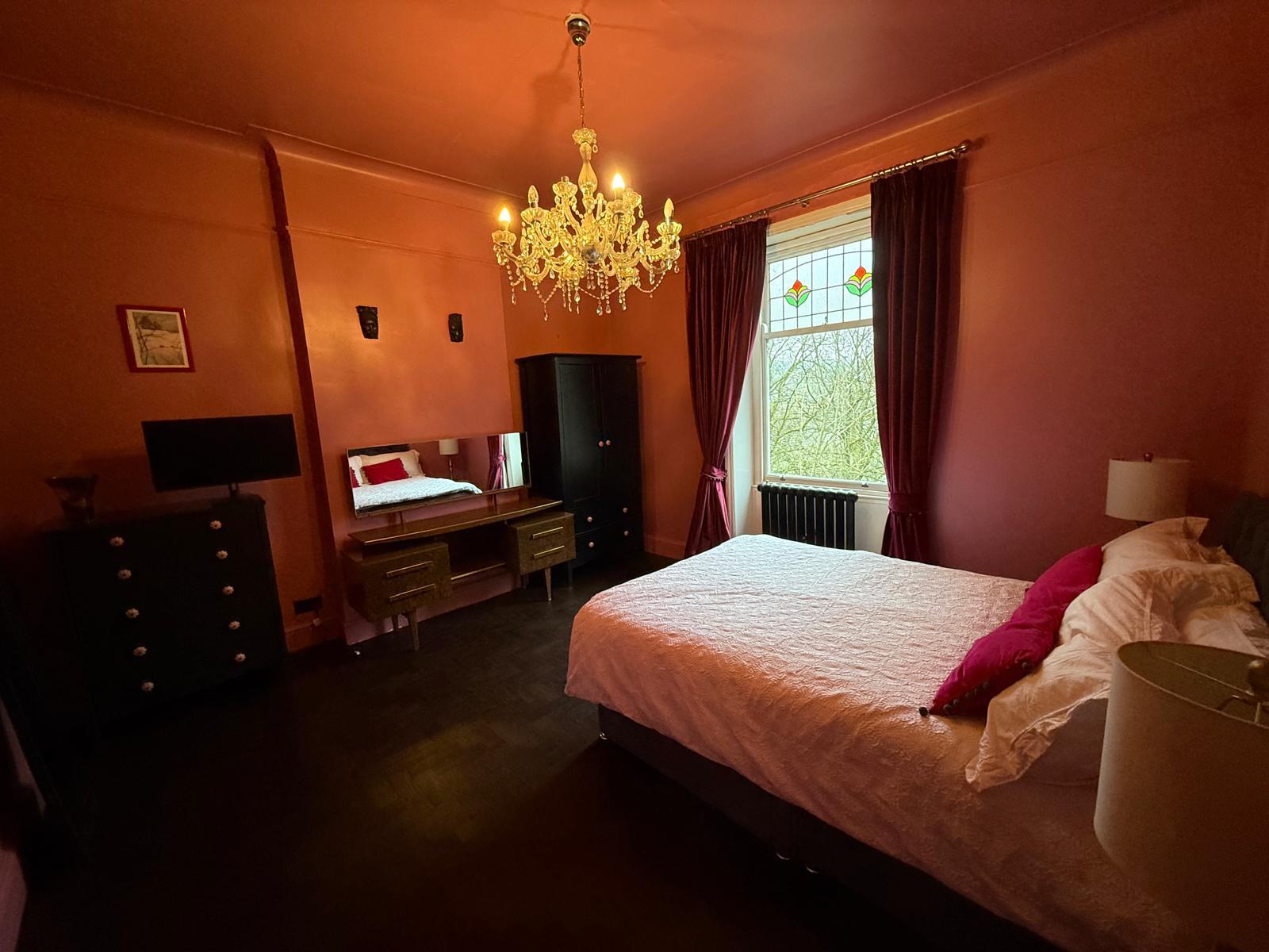 Bedroom with a crystal chandelier, stained glass window and warm lighting
